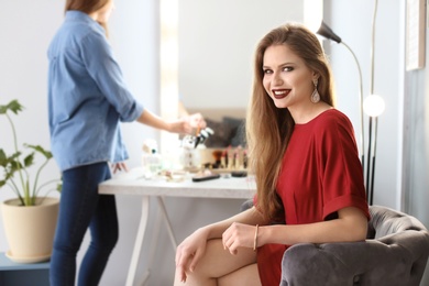 Photo of Beautiful young woman with makeup made by professional artist in dressing room