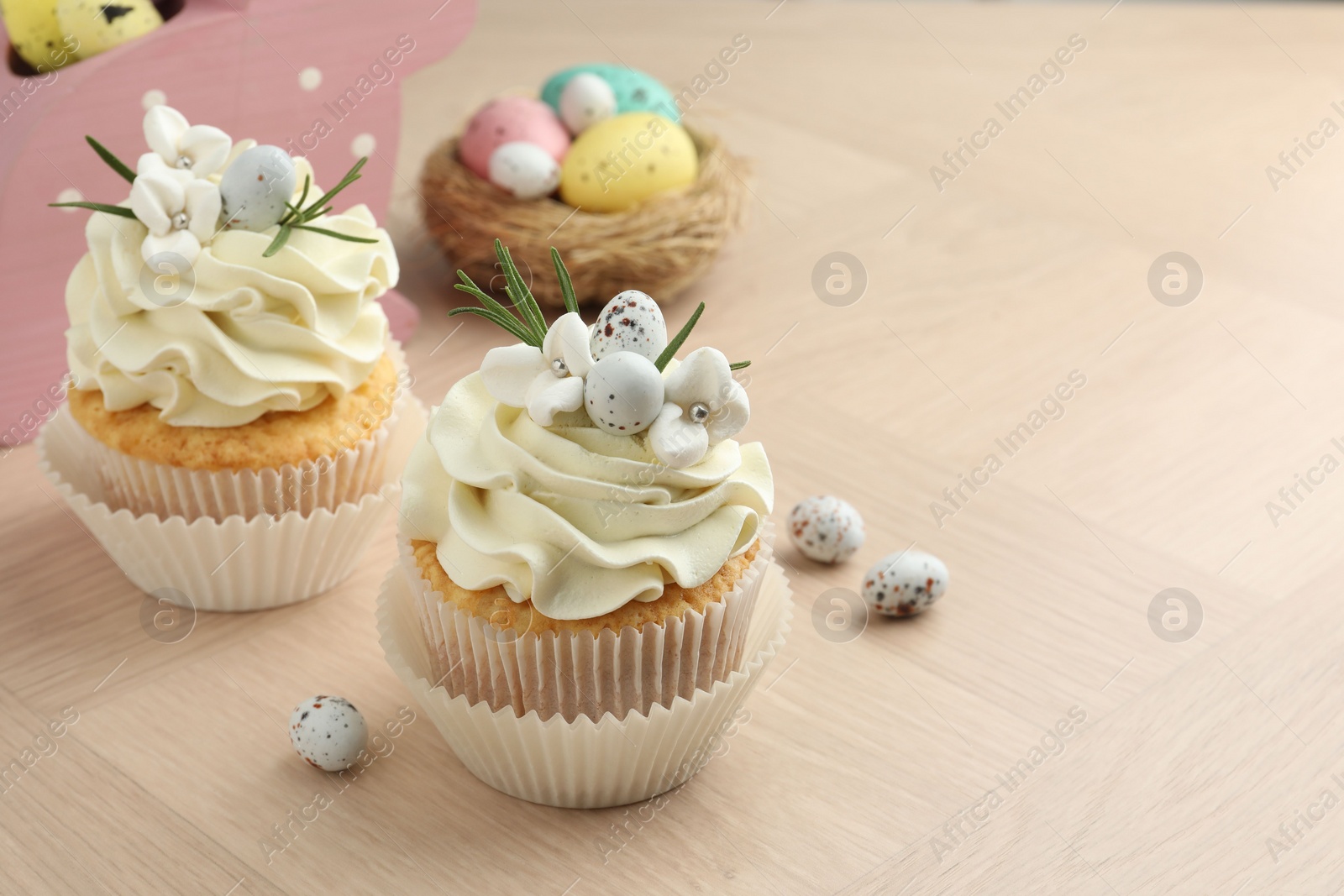 Photo of Tasty Easter cupcakes with vanilla cream on wooden table, space for text