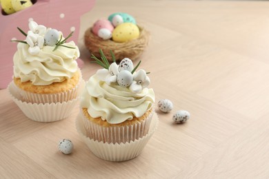 Tasty Easter cupcakes with vanilla cream on wooden table, space for text