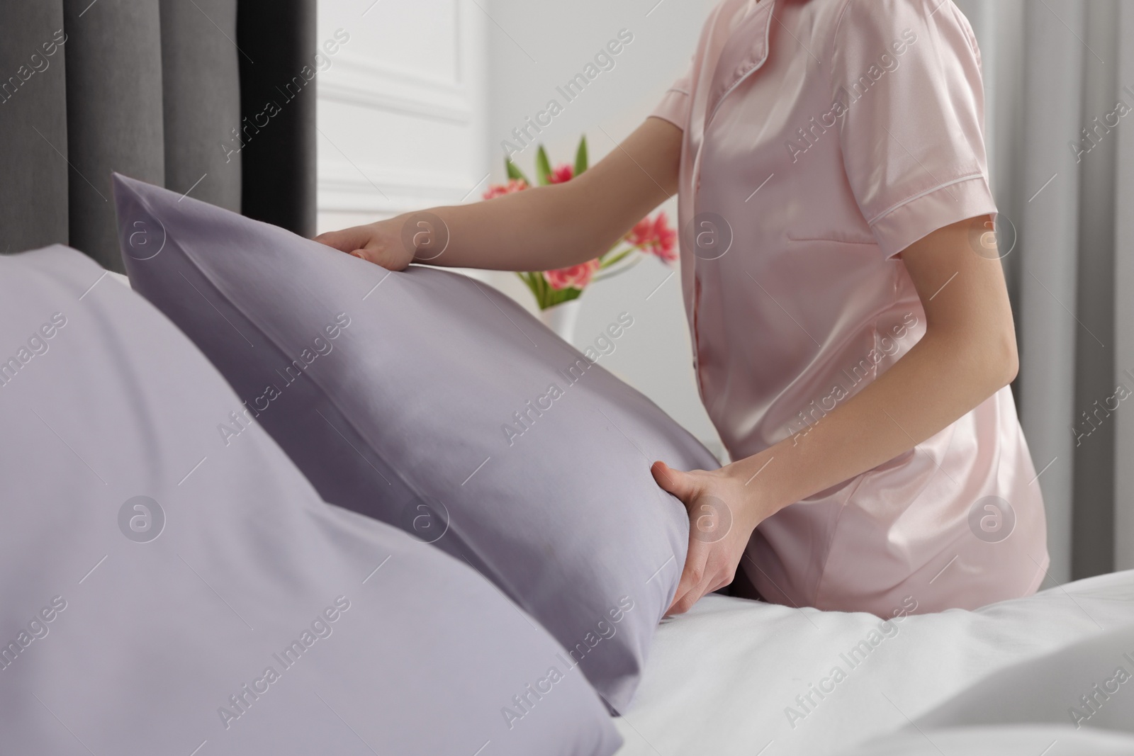 Photo of Young woman making bed in room, closeup