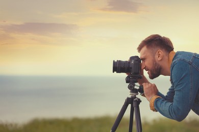 Image of Photographer taking picture of beautiful landscape with professional camera outdoors. Space for text