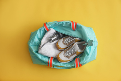 Gym bag with sports equipment on yellow background, top view