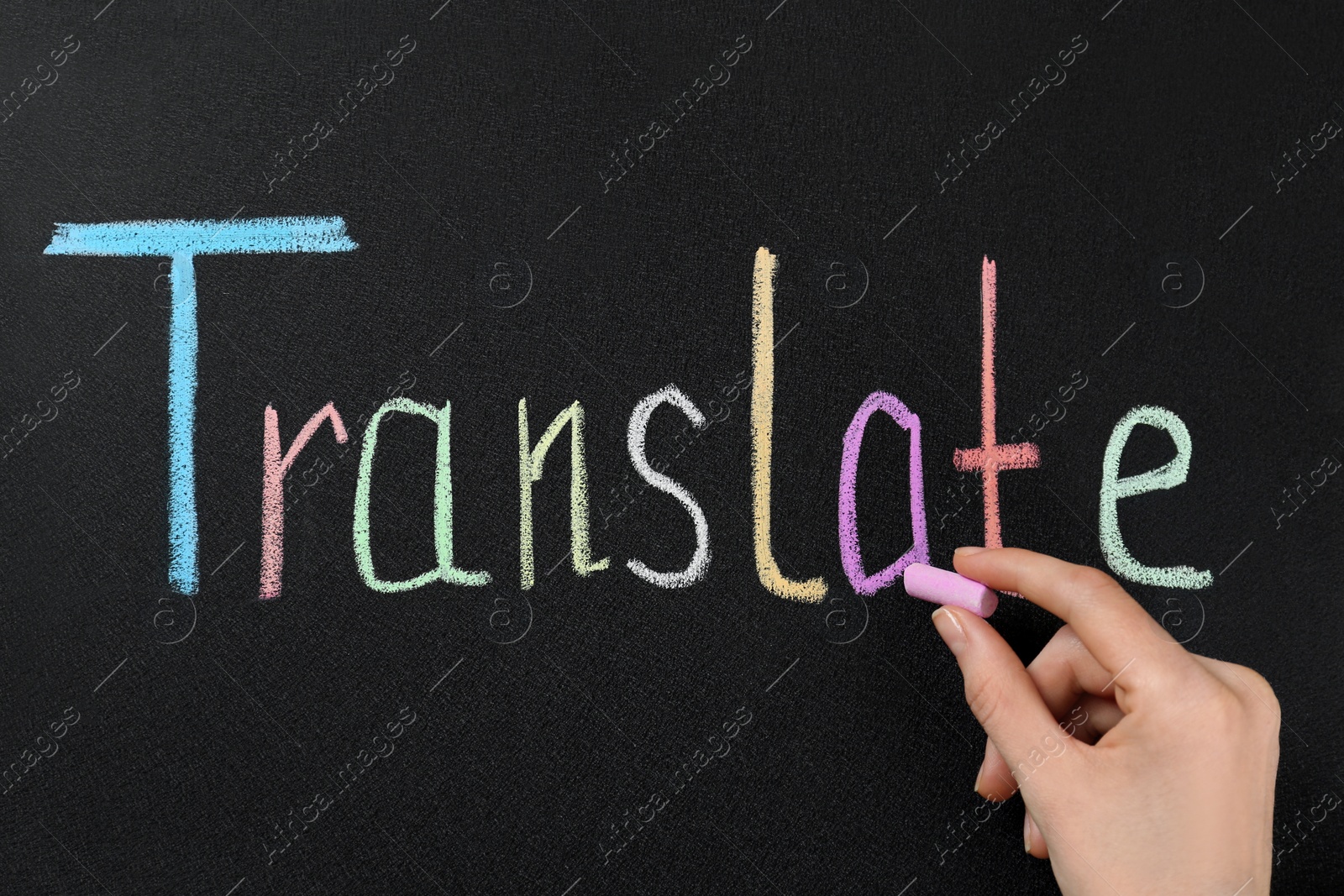 Photo of Woman writing word Translate with chalk on blackboard, closeup