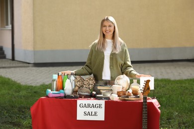 Photo of Woman selling different items on garage sale in yard
