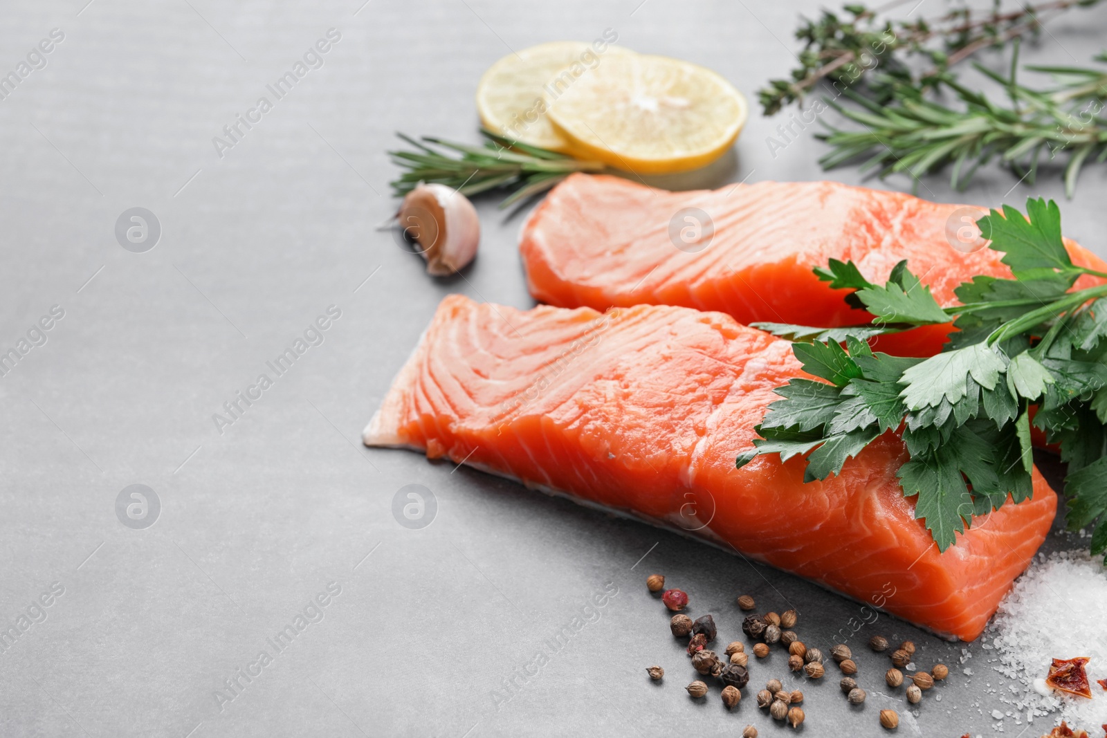 Photo of Fresh salmon and ingredients for marinade on grey table. Space for text