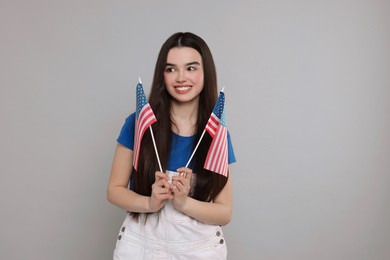 4th of July - Independence Day of USA. Happy girl with American flags on grey background