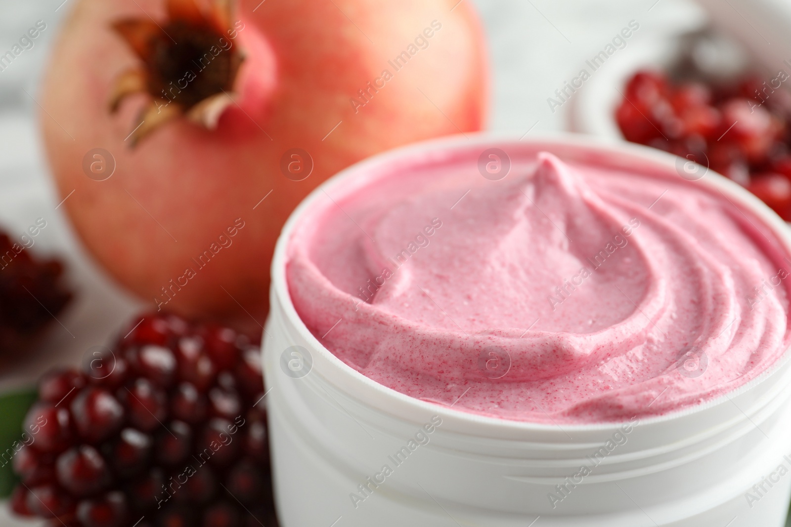 Photo of Jar of facial mask and fresh pomegranate, closeup. Natural organic cosmetics