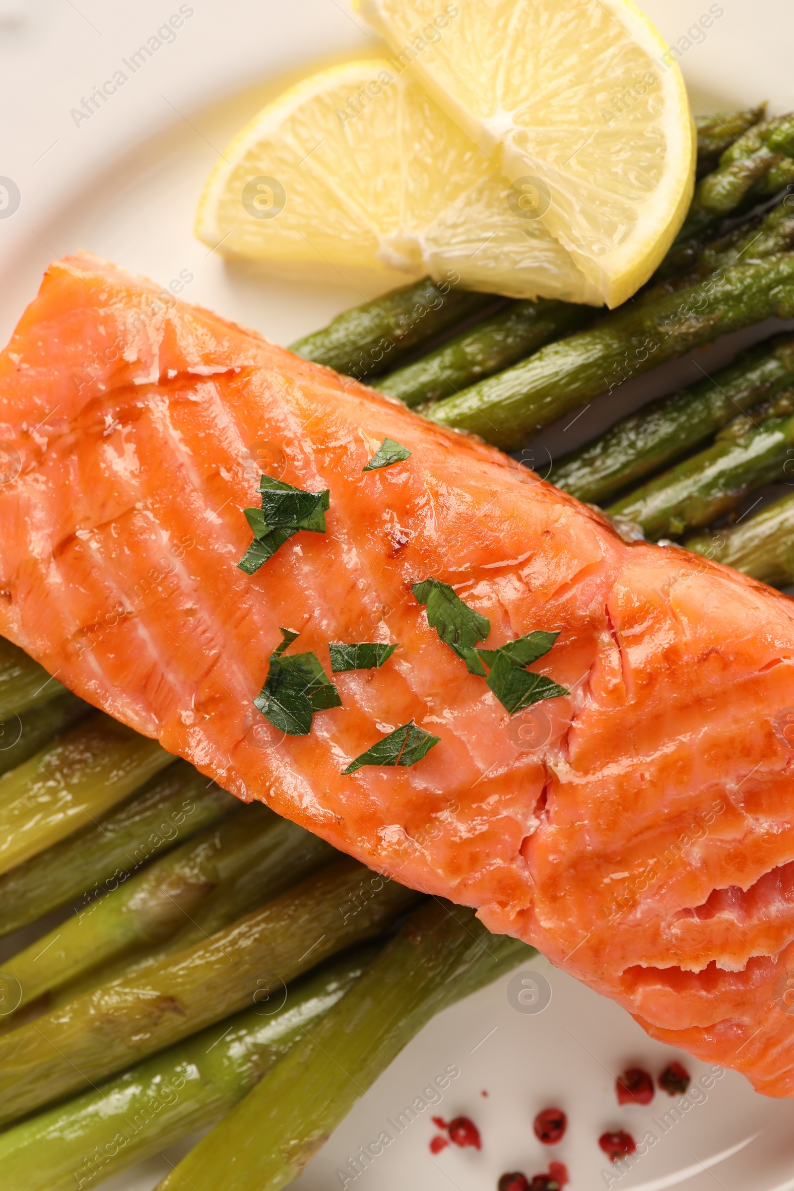 Photo of Plate with tasty grilled salmon, asparagus and lemon, top view