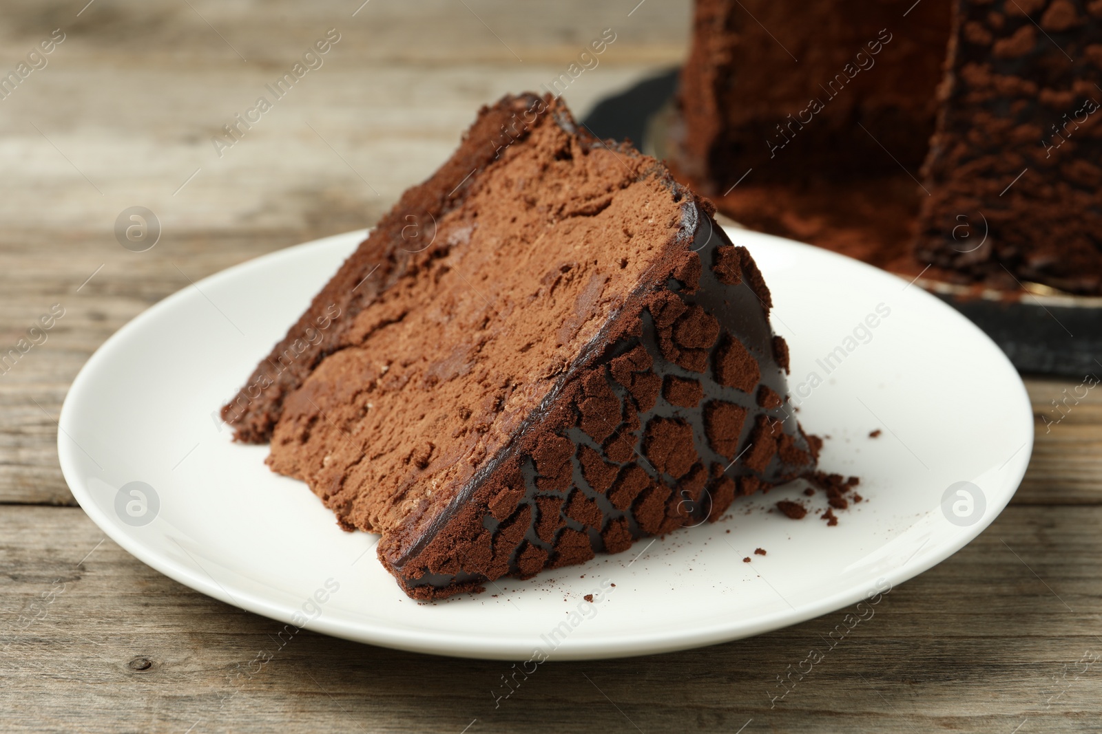 Photo of Piece of delicious chocolate truffle cake on wooden table, closeup