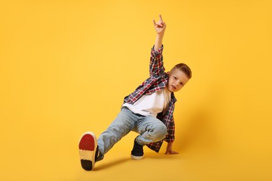 Photo of Happy little boy dancing on yellow background