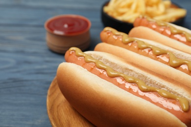 Fresh hot dogs with mustard on wooden table, closeup