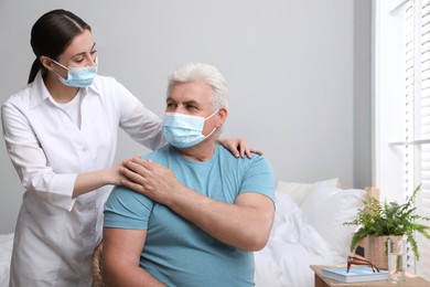 Photo of Doctor taking care of senior man with protective mask at nursing home