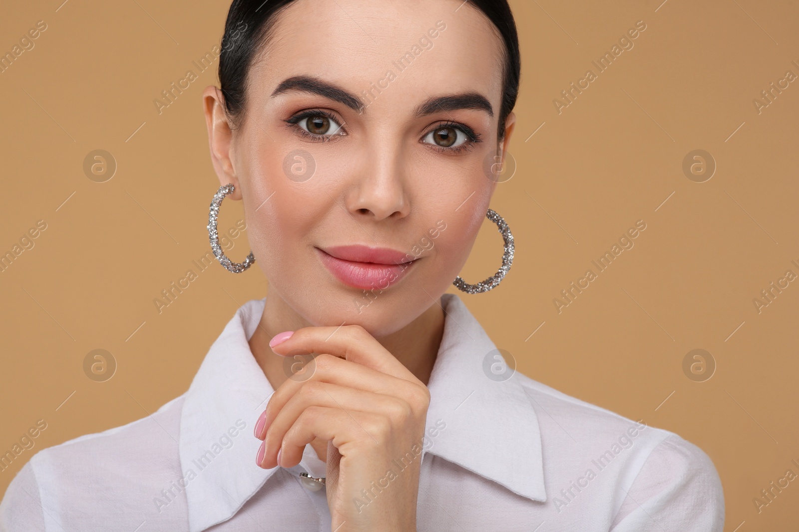 Photo of Beautiful young woman with elegant earrings on beige background