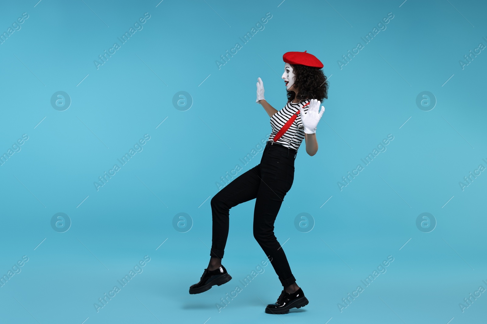 Photo of Funny mime with beret posing on light blue background