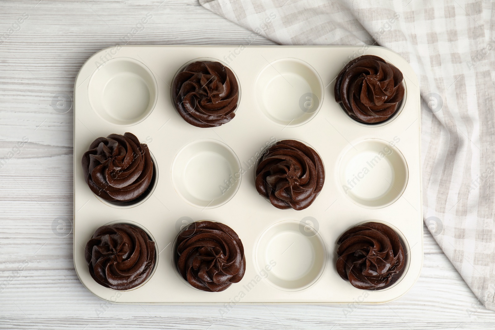 Photo of Delicious chocolate cupcakes with cream in baking tray on white wooden table, top view