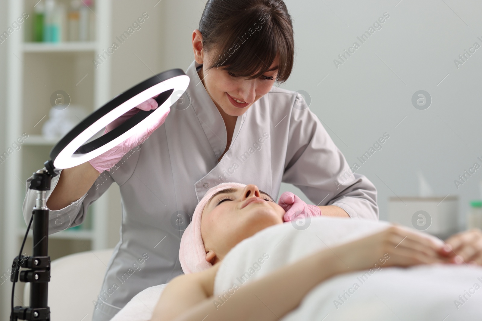 Photo of Cosmetologist making face massage to client in clinic