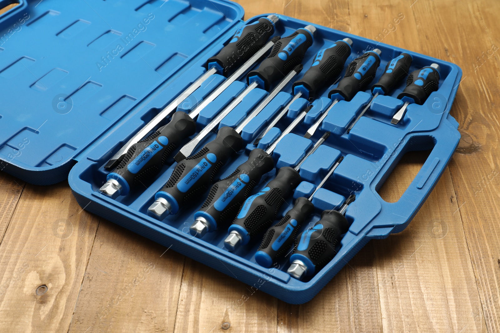 Photo of Set of screwdrivers in open toolbox on wooden table, closeup