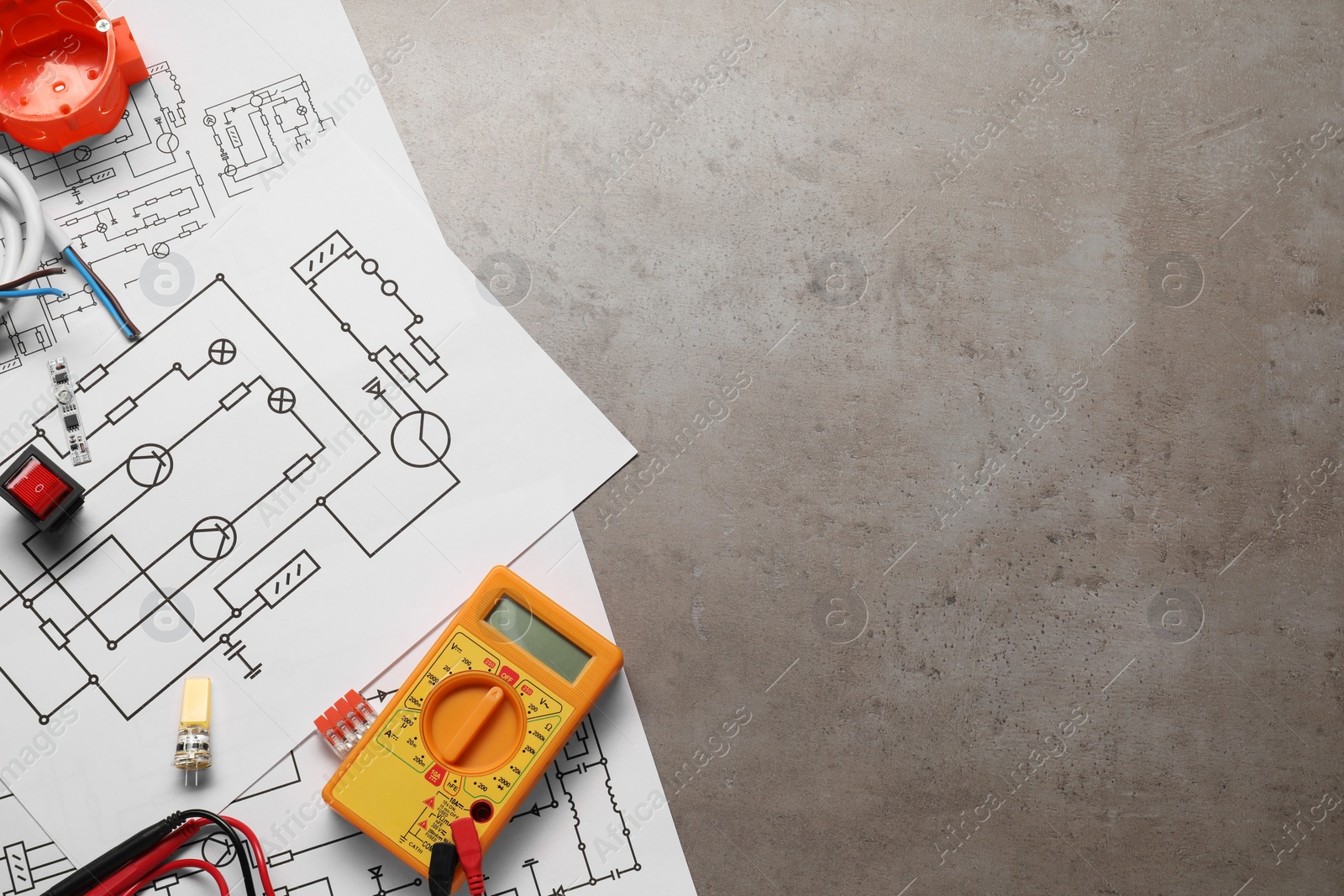 Photo of Wiring diagrams, digital multimeter and other electrician's equipment on grey table, flat lay. Space for text