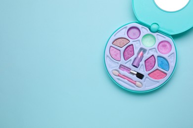 Photo of Decorative cosmetics for kids. Eye shadow palette on light blue background, top view. Space for text