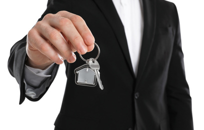 Photo of Real estate agent holding house key with trinket on white background, closeup