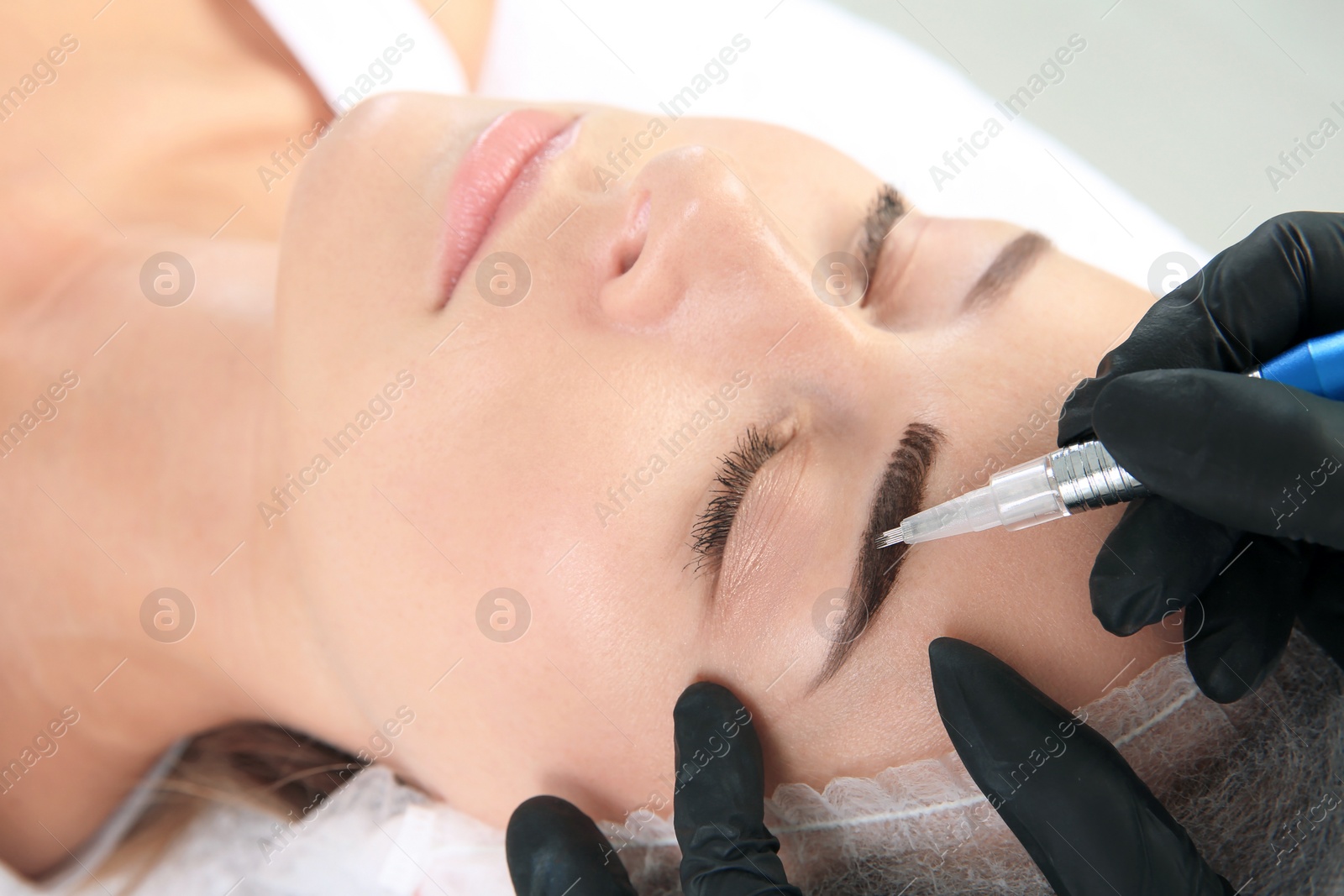 Photo of Young woman undergoing eyebrow correction procedure in salon