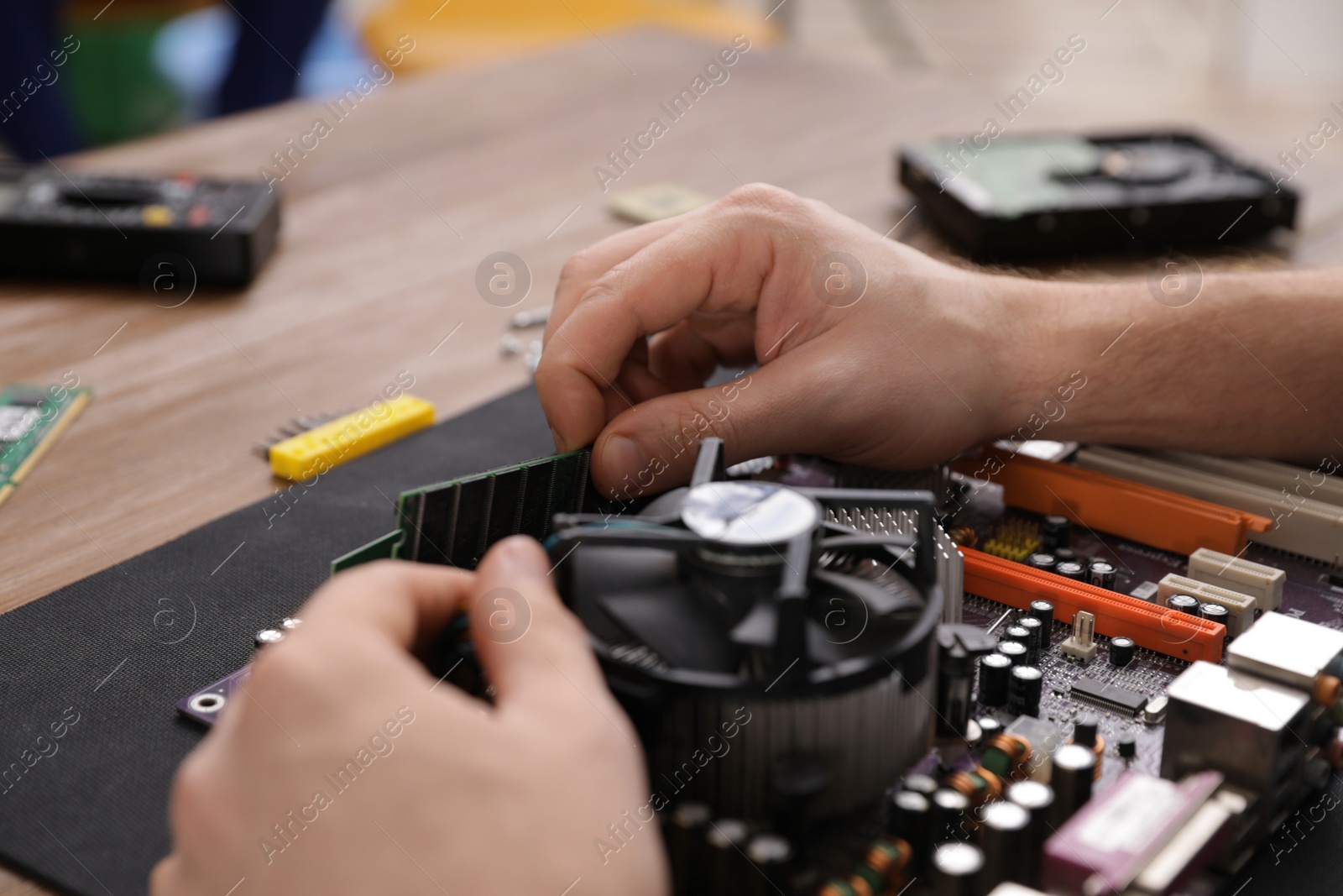 Photo of Male technician repairing motherboard at table, closeup