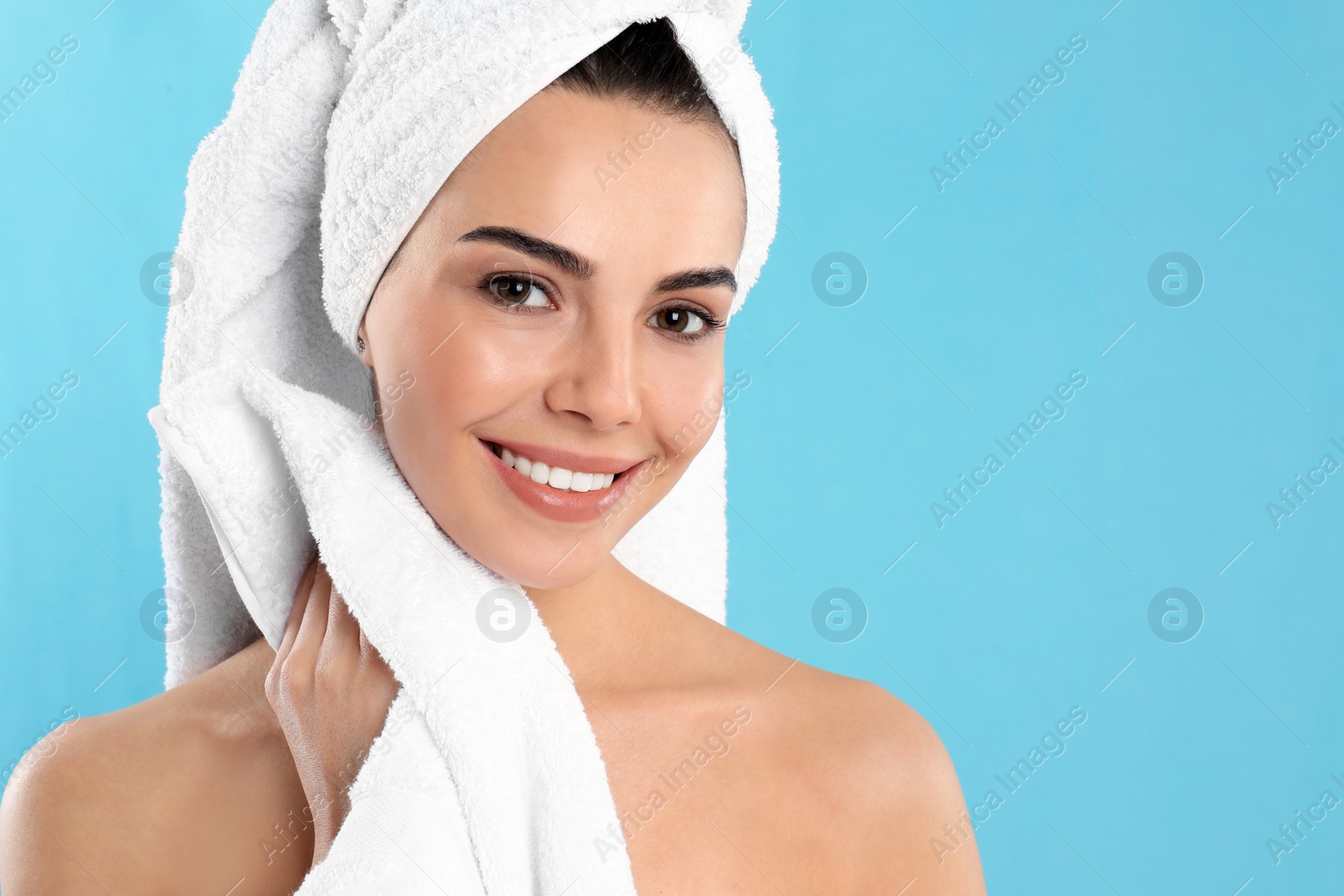 Photo of Young woman wiping body with towel on light blue background