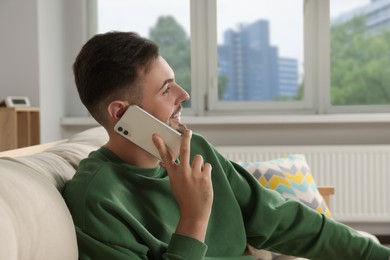 Photo of Handsome man talking on phone in living room
