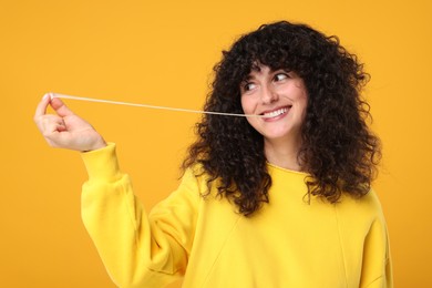Photo of Happy young woman stretching bubble gum on orange background