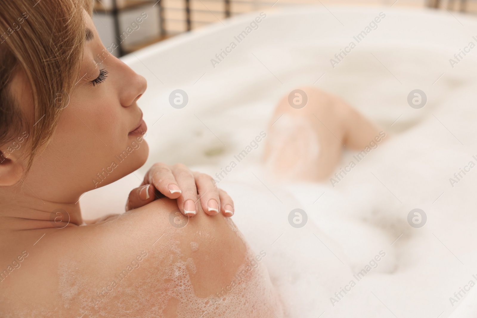 Photo of Beautiful woman taking bath with foam in tub indoors, closeup. Space for text