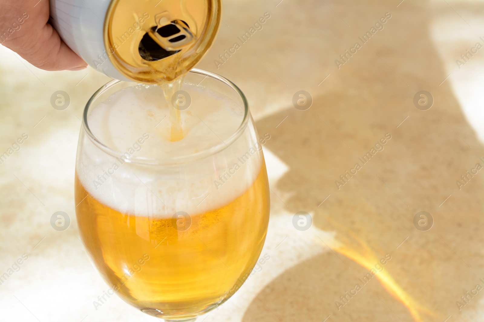 Photo of Man pouring beer from can into glass at table, closeup. Space for text