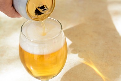 Photo of Man pouring beer from can into glass at table, closeup. Space for text