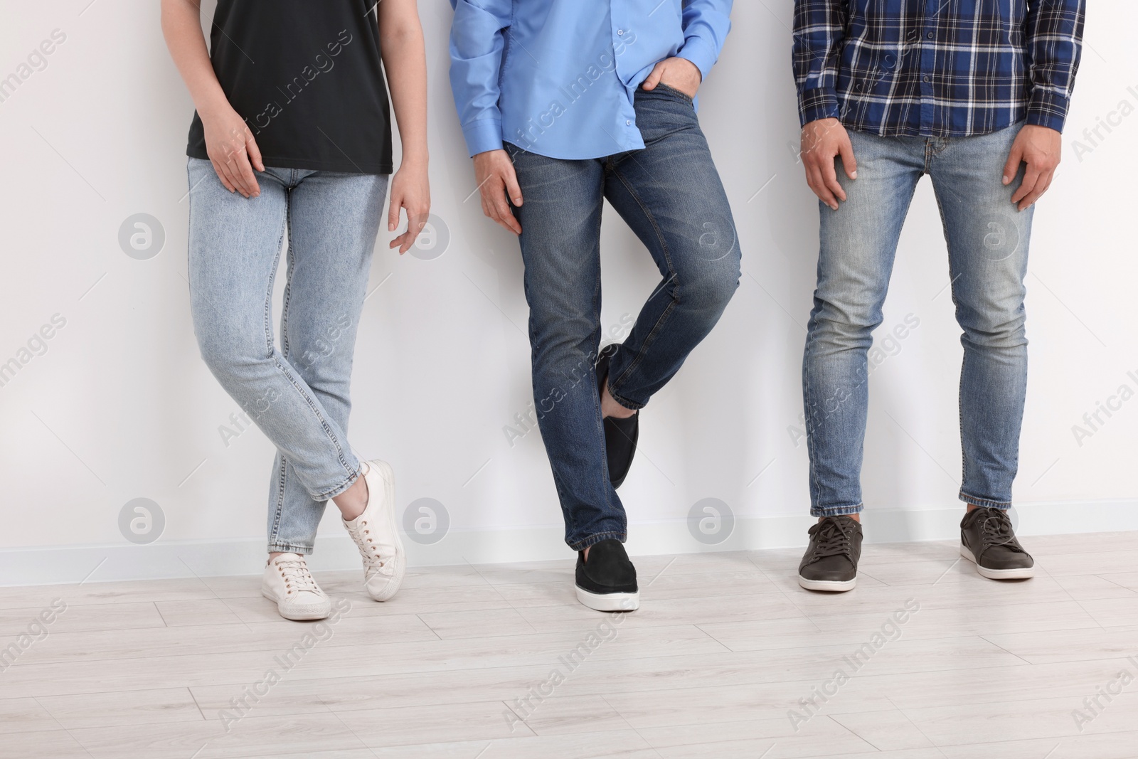 Photo of People in stylish jeans near white wall indoors, closeup