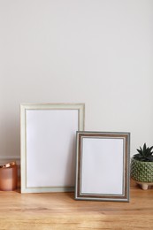 Photo of Empty photo frames and succulent on wooden table indoors