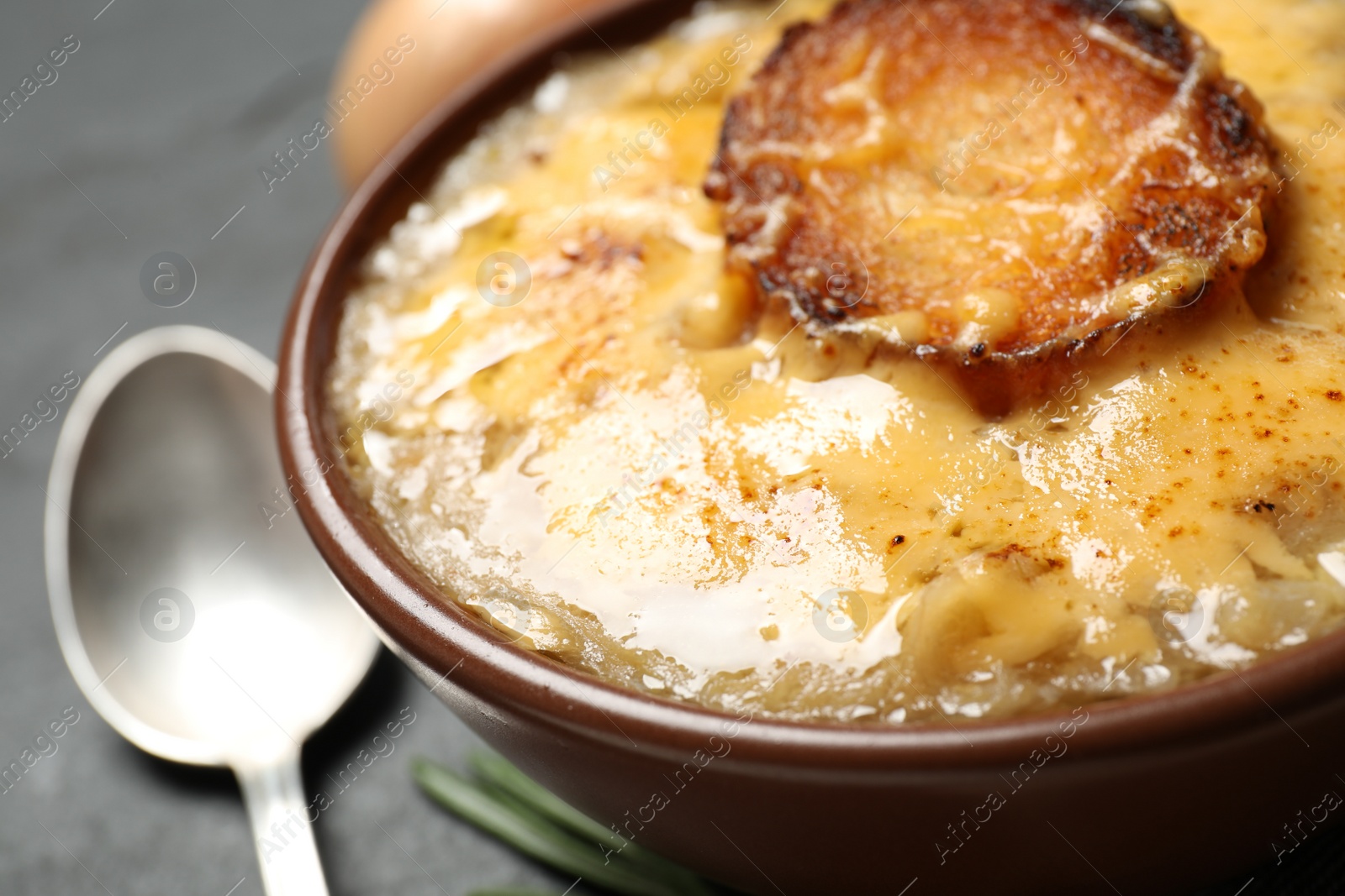 Photo of Tasty homemade french onion soup served in ceramic bowl, closeup