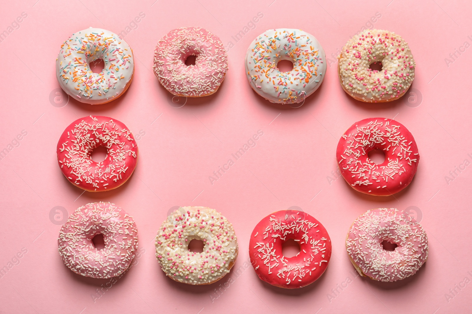 Photo of Frame made of delicious glazed doughnuts on color background, top view