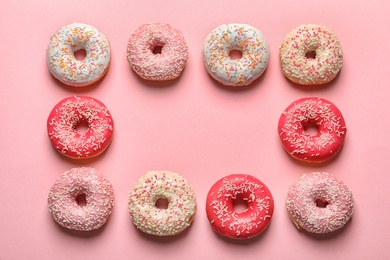 Photo of Frame made of delicious glazed doughnuts on color background, top view