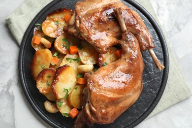 Tasty cooked rabbit meat with vegetables on light grey table, top view