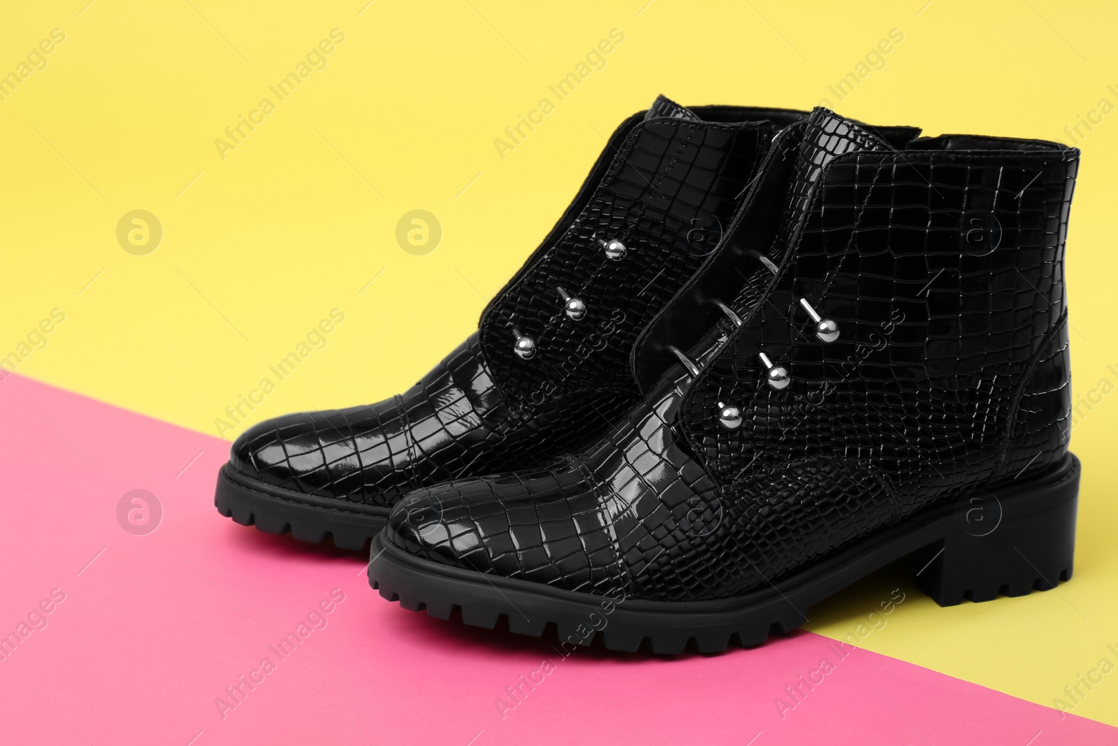 Photo of Pair of stylish ankle boots on color background