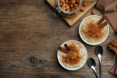 Delicious rice pudding with cinnamon on wooden table, flat lay. Space for text
