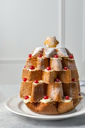 Photo of Delicious Pandoro Christmas tree cake with powdered sugar and berries on white table
