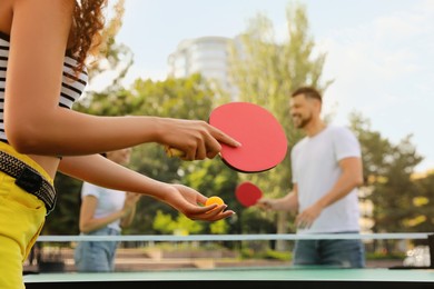 Photo of Friends playing ping pong outdoors, focus on hands