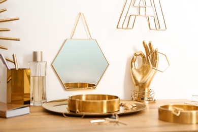 Photo of Composition with gold accessories on dressing table near white wall
