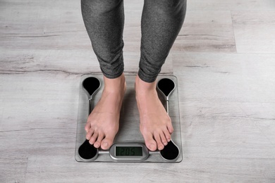 Photo of Young woman measuring her weight using scales on floor, top view. Weight loss motivation