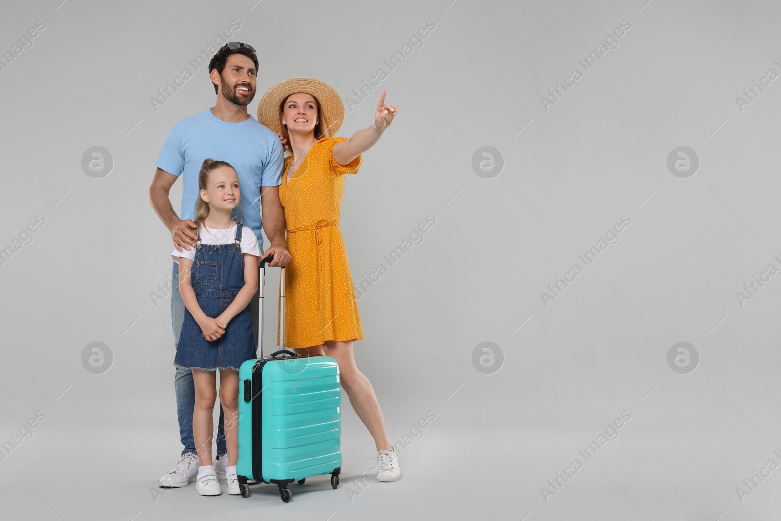 Photo of Happy family with turquoise suitcase on light grey background. Space for text