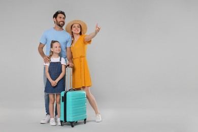 Happy family with turquoise suitcase on light grey background. Space for text