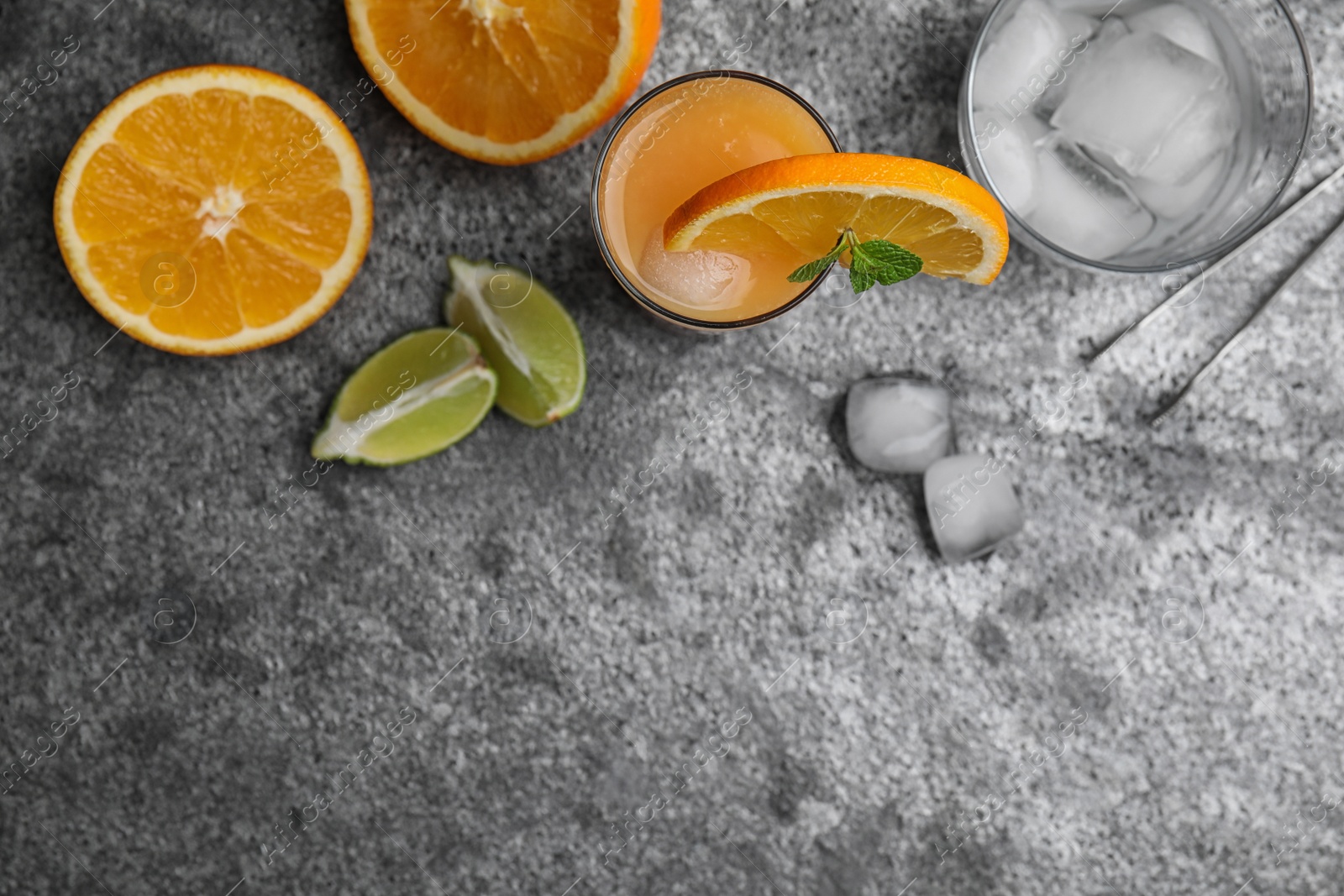 Photo of Fresh alcoholic Tequila Sunrise cocktail on grey table, flat lay. Space for text