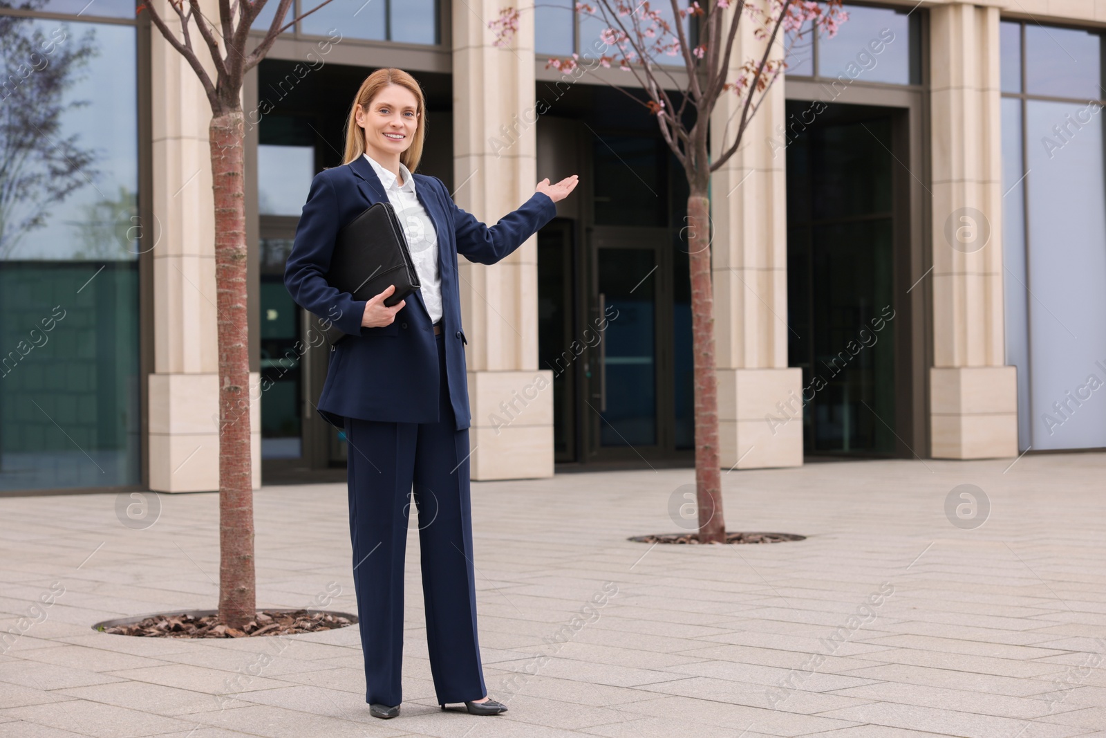 Photo of Female real estate agent with leather portfolio outdoors