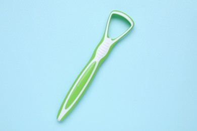 Photo of Green tongue cleaner on light blue background, top view