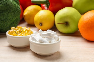 Photo of Dietary supplements. Bowls with different pills near food products on light wooden table, closeup